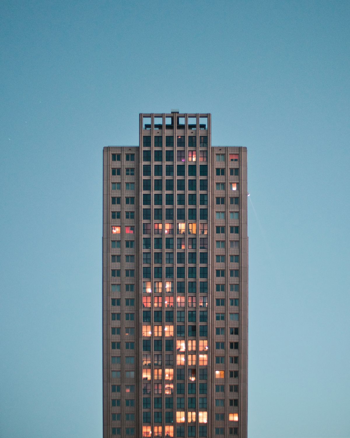 Edificio de viviendas al anochecer con las ventanas iluminadas